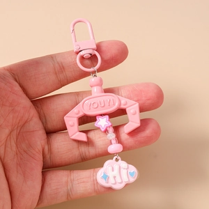 Detailed macro view of pink claw machine keychain with star beads and cloud pendant