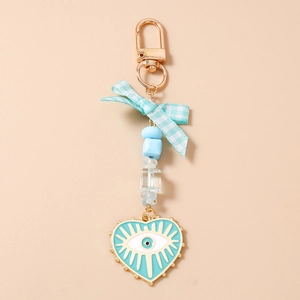 Detailed close-up of blue bow keychain with beaded heart and evil eye charm