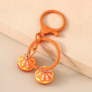 Close-up of realistic peeled orange slice pendants on a matching orange metal keychain
