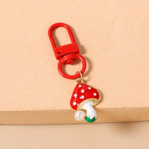 Detail of red mushroom keychain with white faux pearl and metallic lobster clasp