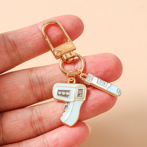 Detail view of medical keychain with thermometer and test tube charms in gold and blue