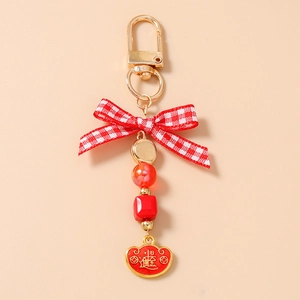Detail of beaded keychain with red bow and golden yuanbao charm with prosperity text