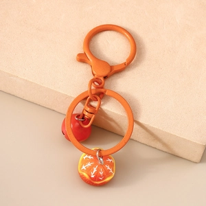 Detail of creative fruit keychain featuring a realistic orange slice and red bell charm