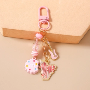 Detail shot of a pink beaded keychain featuring mini guitar, harp and cookie charms
