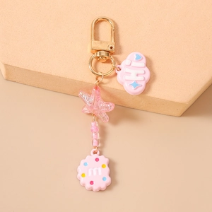 Detailed close-up of pink cloud and biscuit charms on a golden starfish keychain
