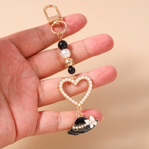 Detail of beaded heart keychain with golden lobster clasp and black enamel flower hat charm