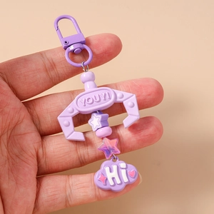 Detailed close-up of a purple crane machine claw keychain with star and cloud charms