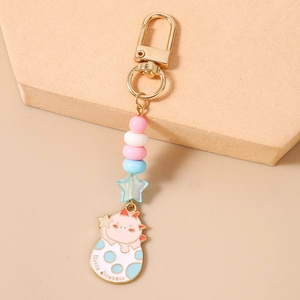 Détail d'un porte-clés œuf de dinosaure avec perles colorées et crochet en métal doré