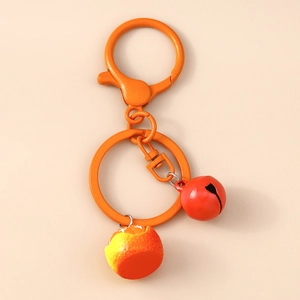 Detail of orange fruit keychain with citrus texture, lobster clasp, and red bell charm