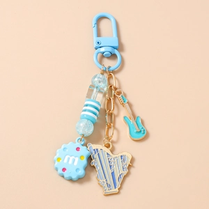 Close-up of blue beaded keychain with guitar, harp and cookie charms on gold chain
