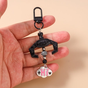 Detail of black mechanical claw keychain with beaded strap and white cloud pendant