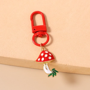 Detailed macro view of a red mushroom keychain with white spots and a green leaf detail
