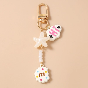 Detailed shot of cute golden keychain featuring cloud, starfish, and m-letter biscuit charms
