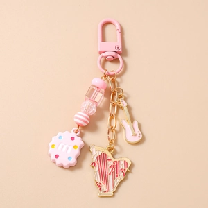 Detail view of pink guitar and harp charms with beaded keychain and biscuit pendant