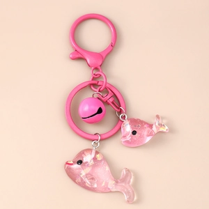 Detailaufnahme der rosa Delfin-Anhänger mit Glitzerpartikeln und Glocke am Schlüsselanhänger