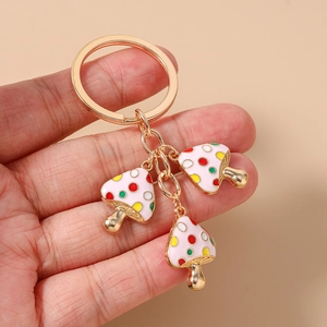 Detail eines goldenen Schlüsselanhängers mit drei bunten gepunkteten Pilzanhängern in Rosa