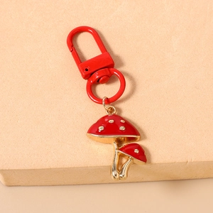 Detail of red mushroom keychain with gold alloy finish and white speckled enamel