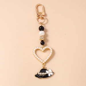 Detail of beaded keychain with gold lobster clasp, heart charm and mini black top hat