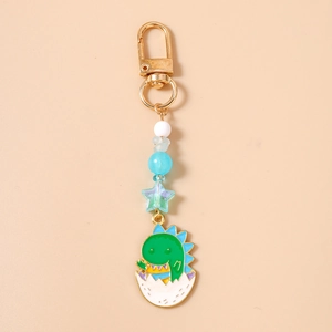 Détail d'un porte-clés dinosaure vert mignon avec perles étoiles et fermoir doré chic