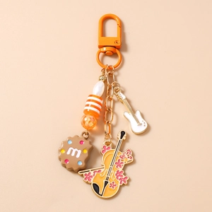 Detail of beaded keychain with guitar and harp charms on orange background