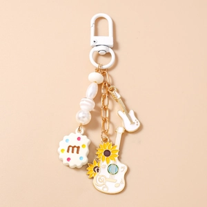 Detailed shot of guitar charms, white pearls, and flower pendants on a gold keychain