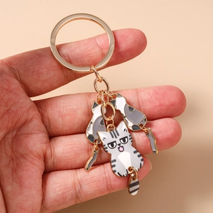 Détail d'un porte-clés en métal doré avec des pendentifs de chat en émail coloré