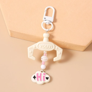 Close-up of crane machine keychain with beads and cloud pendant on a beige stand