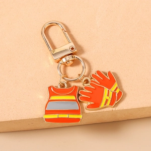 Detail of firefighter keychain featuring enamel safety vest and orange gloves charms