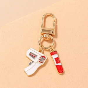 Detail of gold medical keychain with enamel infrared thermometer and blood test tube charms