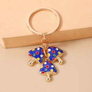 Detailansicht von drei blauen Emaille-Pilzanhängern an einem goldenen Schlüsselring