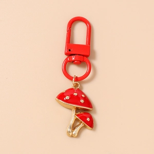 Detail shot of dual mushroom keychains with red glossy caps and gold alloy finish