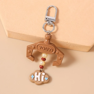 Detail of claw-shaped keychain with beads and cloud pendant on a beige display stand