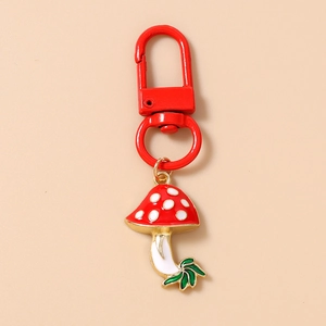 Detailed close-up of a red mushroom keychain with white spots and a green leaf charm