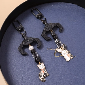 Macro detail of punk skull cat and rabbit keychains with striped beads and metal hooks