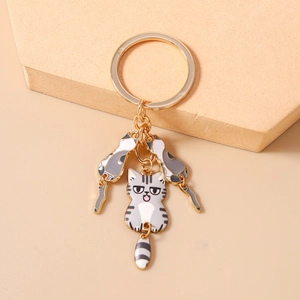 Détail de trois breloques de chat de dessin animé uniques sur un porte-clés doré en métal