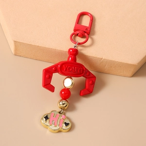 Detail of red claw machine keychain with metal hook, beaded accent and cloud charm