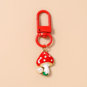 Detail of red mushroom keychain with white spots and a delicate white imitation pearl charm