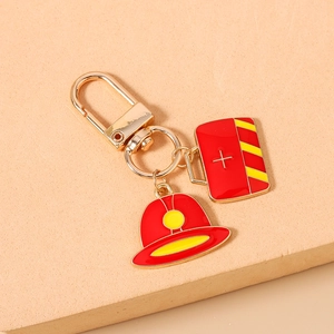 Detail of firefighter keychain featuring red helmet and emergency box enamel charms
