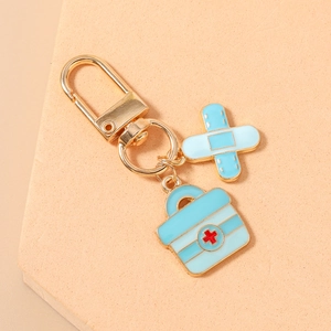 Detail of medical keychain with blue first aid kit and bandage charms in gold finish