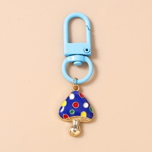 Detail of blue mushroom keychain with colorful dots and golden alloy finish