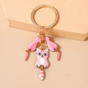 Gros plan sur un porte-clés doré avec trois pendentifs chat en émail rose à rayures