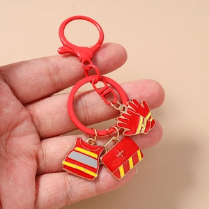 Handheld detail of red fire hydrant keychain with vest, medical kit and gloves charms