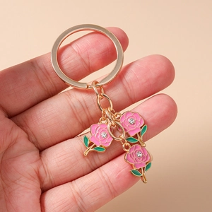 Detailed view of gold keychain featuring pink enamel roses and sparkling crystals
