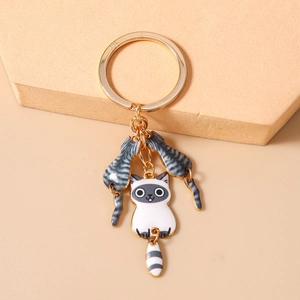 Détail d'un porte-clés doré avec des breloques de chat mignon et pendentif queue rayée