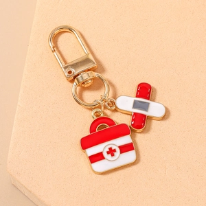 Detail of medical themed keychain with first aid box and bandage pendants in gold finish