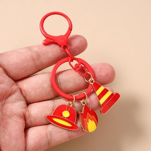 Close-up of firefighter keychain with red flame and helmet charms held in hand
