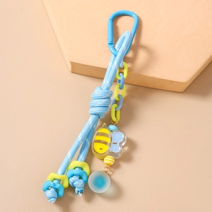 Détail d'un porte-clés en corde bleue avec breloque abeille et perle mate sur un support