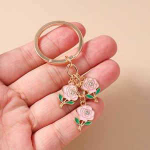 Close-up of pink enamel rose keychain with gold metal ring and sparkling crystal center