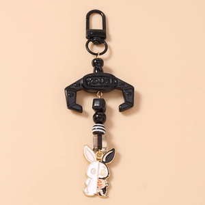 Macro detail of a gothic bunny keychain with black and white beads on pink background
