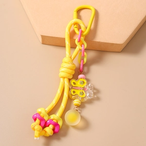 Détail du porte-clés en corde tressée jaune avec pendentif papillon et mousqueton